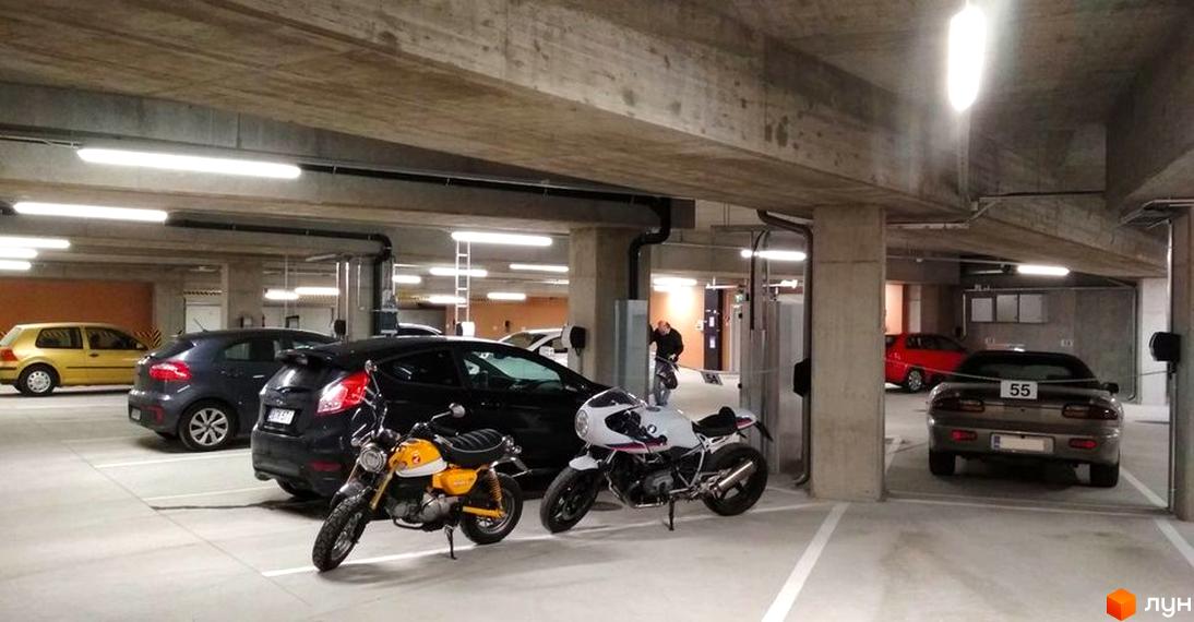 Підземний паркінг Житлового комплексу Uzh Towers з припаркованими автомобілями та мотоциклами.