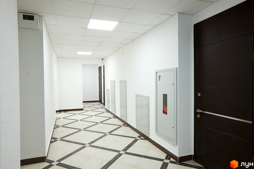 Коридор у новобудові ЖК Столичний з плиткою на підлозі та дверима. Огляд внутрішнього простору житлового комплексу.