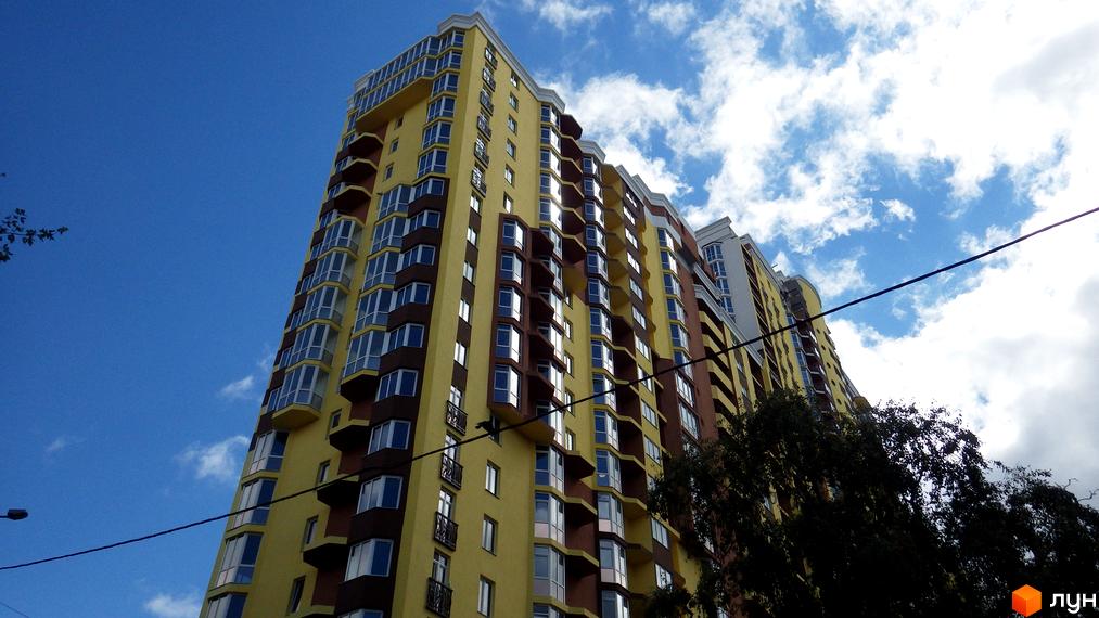 Новобудова жовто-коричневого кольору з численними балконами та вікнами на вул. Коперника, 7 під блакитним небом.