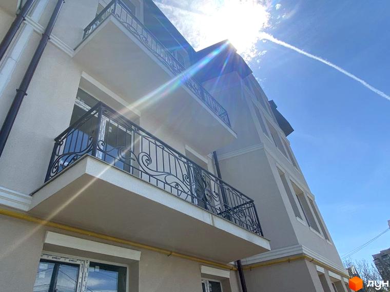 Вид на фасад будівлі Житлового комплексу по вул. Академіка Вернадського (Тульська), 21а. Зображення показує балкони з кованими перилами та сонячне небо.