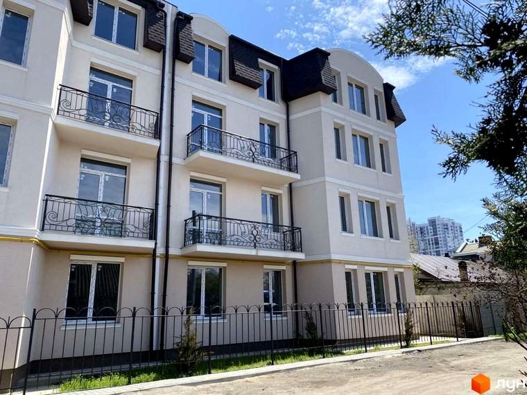 Зображення фасаду будинку Житловий комплекс на вул. Академіка Вернадського (Тульська), 21а з кованими балконами та огорожею. На передньому плані - прибудинкова територія з рослинністю.