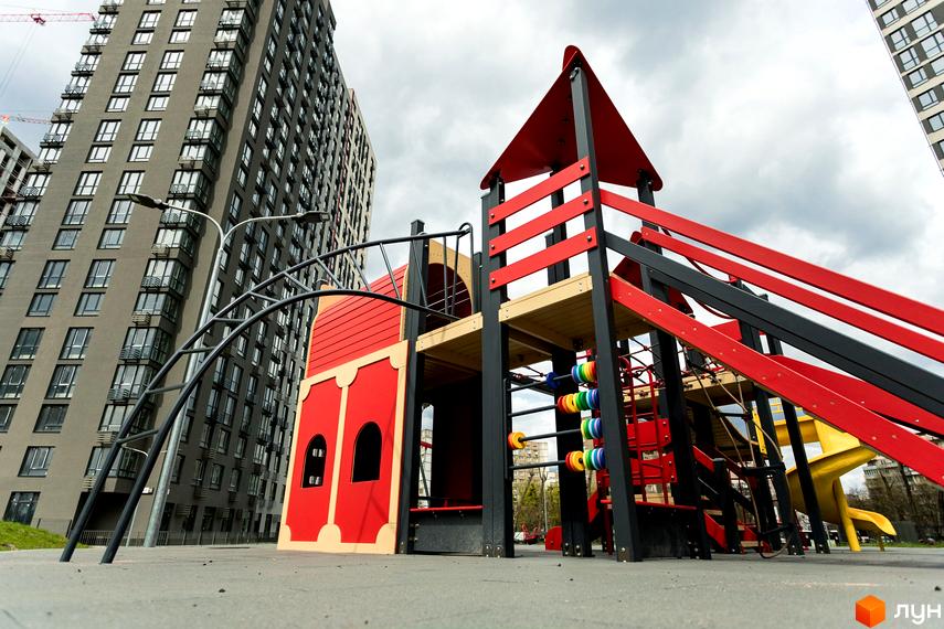 Житловий комплекс Варшавський Плюс: сучасна архітектура багатоповерхових будинків та дитячий майданчик з яскравими елементами.