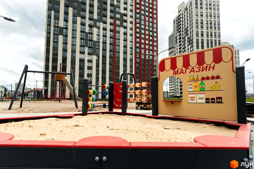 Новобудова ЖК Варшавський Плюс з дитячим майданчиком та пісочницею. Сучасний житловий комплекс з багатоповерховими будинками та ігровою зоною для дітей.