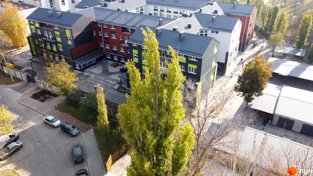 Житловий комплекс Park Stone з фасадами чорного, червоного та салатового кольорів. На прибудинковій території розташовані паркувальні місця та зелені насадження.