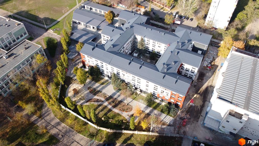 Вид згори на житловий комплекс Парк Стоун з білими фасадами та сірими дахами, що оточує внутрішній двір з ландшафтним дизайном та дитячим майданчиком.