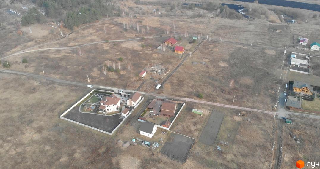 Зображення житлового будинку з червоним дахом та великою прибудинковою територією. Поруч розташовані інші будинки та дорога.