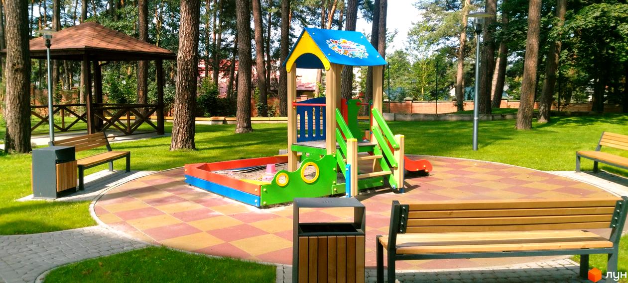 Дитячий майданчик та альтанка в ЖК Грінвуд. Зелена зона з лавками та урнами біля дитячих атракціонів.