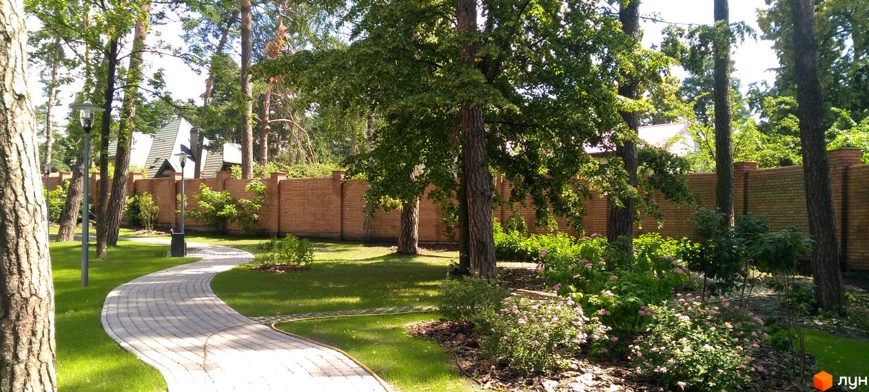 Житловий комплекс Грінвуд: оглядовий майданчик з цегляною стіною та доглянутою територією. Зелена зона з доріжкою з плитки та рослинами.