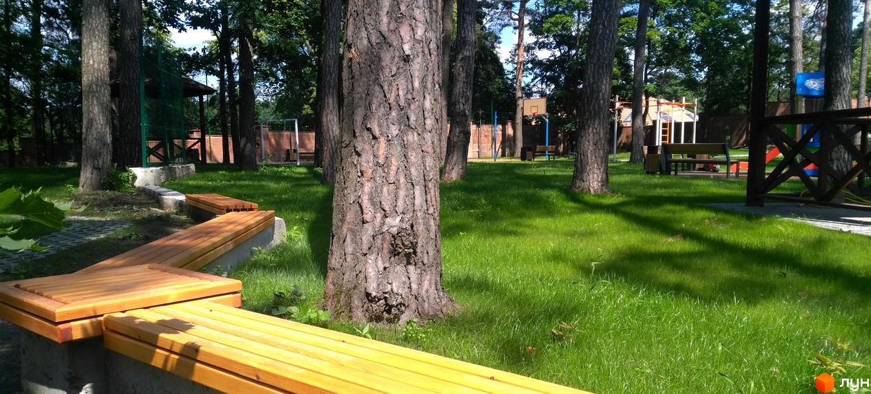 Житловий комплекс Грінвуд: зелена зона з лавками та дитячий майданчик. Паркова зона з деревами та місцями для відпочинку.