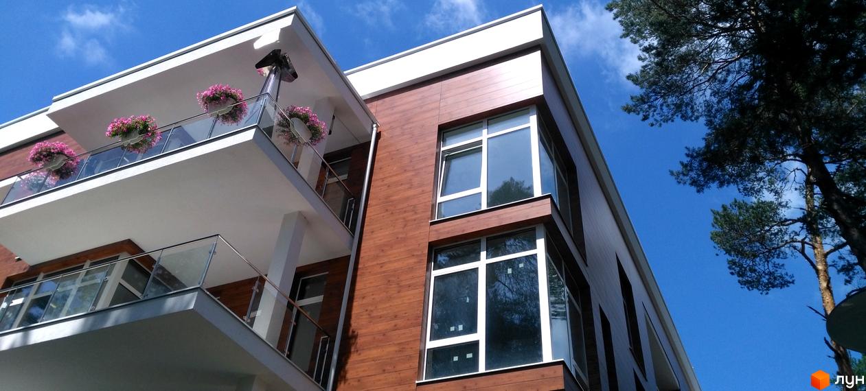 Житловий комплекс Грінвуд: фасади будинку з дерев'яним оздобленням та балконами з квітами. Сучасна архітектура новобудови.