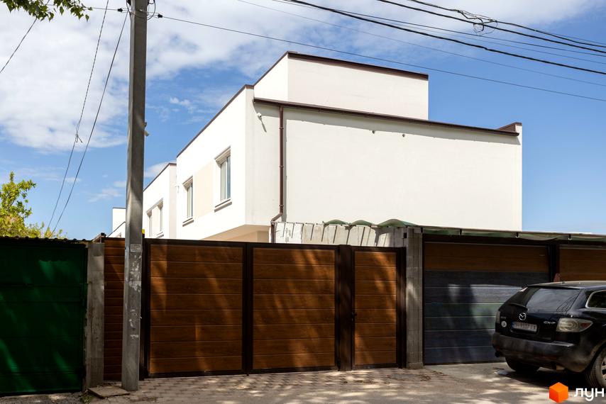 Новобудова на вул. Сергія Шелухина (Олександра Невського), 54, з дерев'яними воротами та автомобілем на прибудинковій території.