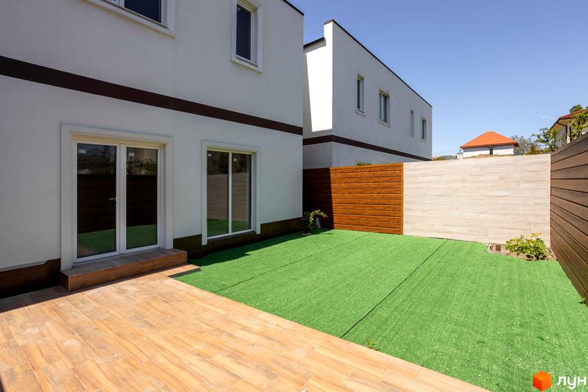 Новобудова на вул. Сергія Шелухина (Олександра Невського), 54, з білими стінами, коричневою обшивкою та зеленим газоном. Прибудинкова територія з дерев'яним патіо та парканом.