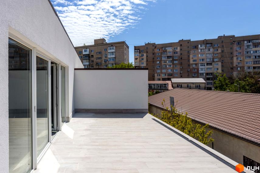 Вид з тераси на сучасні багатоповерхові будинки. Зовнішній вигляд новобудови з білими стінами та великими вікнами.