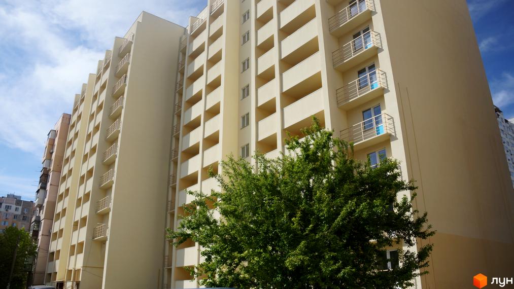 Фасад новобудови на вулиці Генерала Бочарова, 45, з численними балконами та вікнами. На передньому плані зелене дерево.