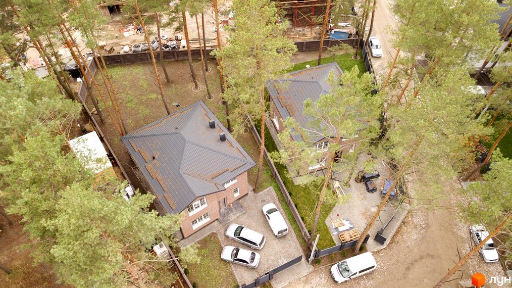 Котеджне містечко Квітка Полонини з будинками з червоної цегли та темною покрівлею, з паркуванням для автомобілів та зеленими насадженнями.