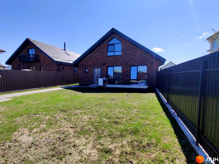 Котеджне містечко КМ Одноповерховий Київ - Мархалівка. Цегляний будинок з великими вікнами та доглянутою прибудинковою територією під блакитним небом.