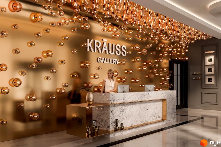 Вхідна група Житлового комплексу Krauss Gallery з золотистою стіною, оздобленою сферичними світильниками, та білою мармуровою стійкою рецепції.