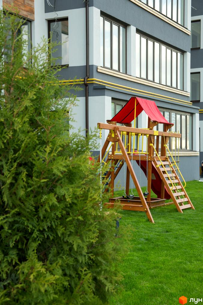 Зовнішній вигляд будинку в Житловому комплексі Cофія з дитячим майданчиком та зеленим газоном.