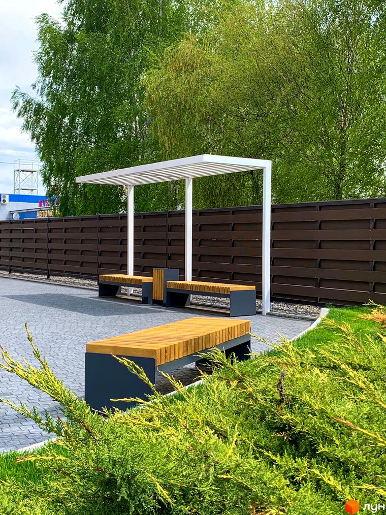 Житловий комплекс Cофія: лави для відпочинку під навісом, бруківка та зелені насадження на прибудинковій території.