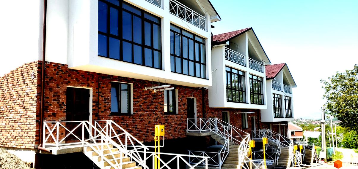 Зовнішній вигляд таунхаусів Garden House у Рівному. Будинки з цегляним фасадом та великими вікнами, поруч сходи та огородження.