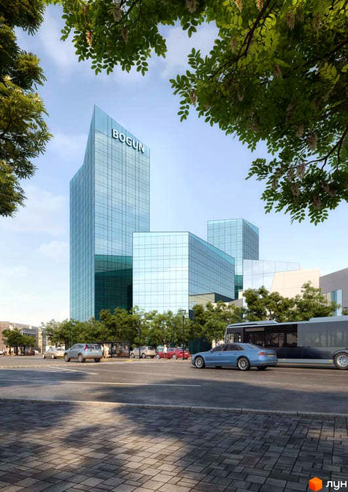Висока скляна будівля Комплексу Bogun з похилим дахом, оточена деревами, дорогою та автомобілями.