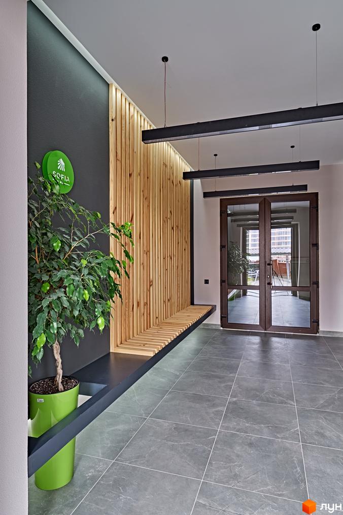 Інтер'єр вхідної групи Житлового комплексу Sofia Residence з озелененням та дерев'яними елементами декору.