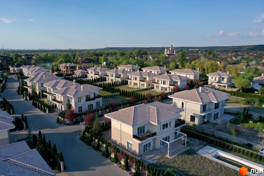 Вид на будинки в Котеджному містечку Золоче Прованс з двоповерховими будинками з сірою черепицею та доглянутою територією з деревами.