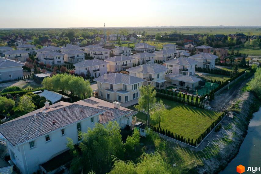 Зображення котеджів в Містечку котеджів Золоче Прованс. Білі будинки з сірими дахами, доглянуті газони та зелені насадження.