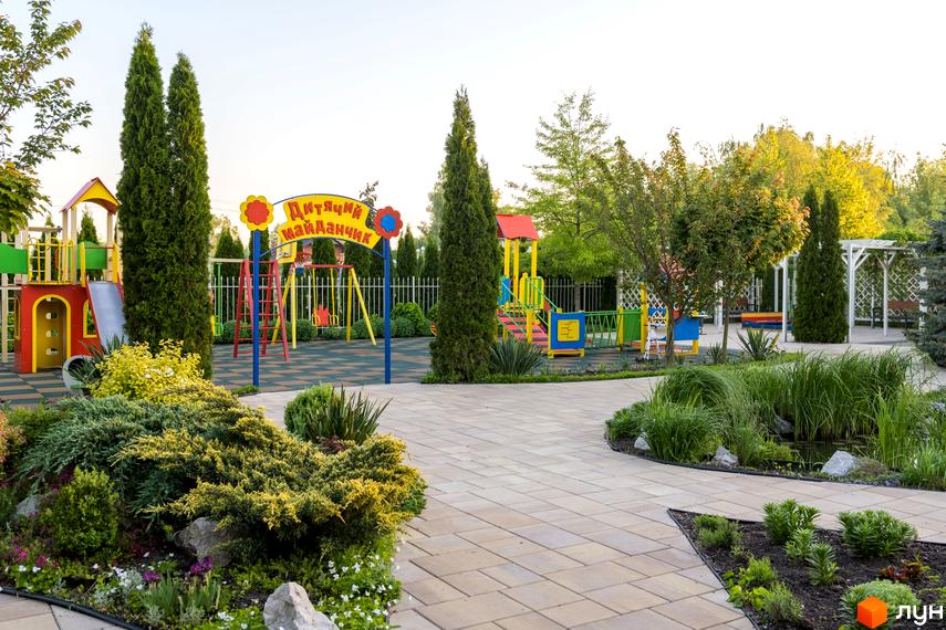 Дитячий майданчик на території Котеджного містечка Золоче Прованс. Ігрові конструкції серед зелених насаджень та доглянутих газонів.