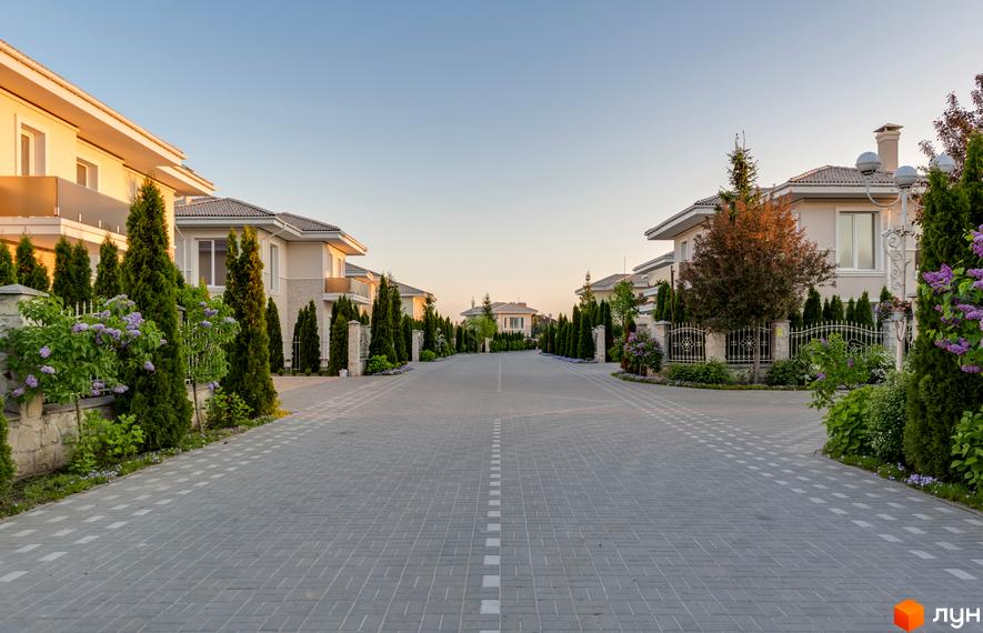 Будинки з бежевими фасадами в Містечку котеджів Золоче Прованс з брукованою дорогою та зеленими насадженнями.