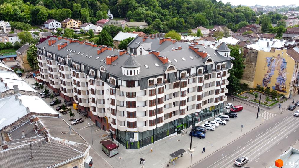 Житловий комплекс Львівський дворик – це багатоповерхова новобудова з еркерними вікнами та балконами. Навколо будівлі розташовані дороги, паркувальні місця та зелені насадження.