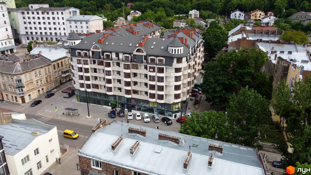 Новобудова Львівський дворик з багатоповерховими будинками та зеленою прибудинковою територією. Зовнішній вигляд будівель з численними вікнами та балконами.