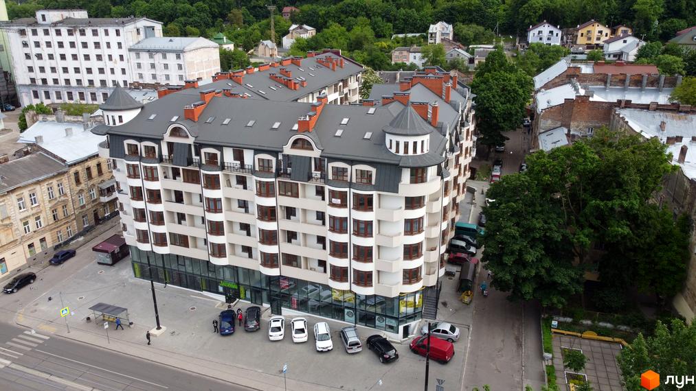 Житловий комплекс Львівський дворик - це багатоповерхова новобудова з еркерними вікнами та балконами. Навколо будинку розташована прибудинкова територія з доріжками та автомобілями.