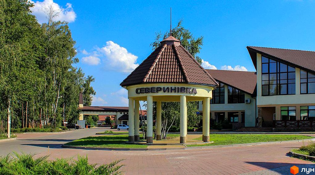 Вхідна зона житлового комплексу КМ Северинівка з сучасною архітектурою та зеленими насадженнями навколо.
