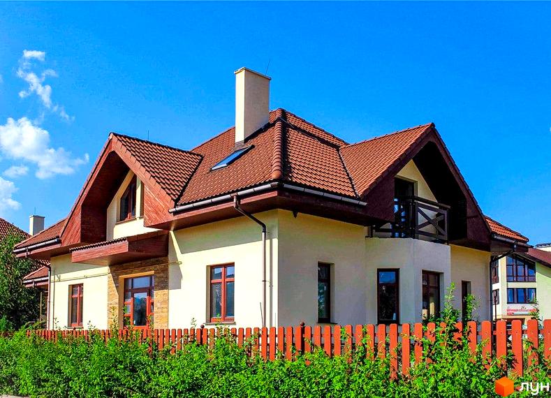 Зображення будинку в Котеджному містечку Северинівка з коричневою черепицею на даху та терасою. Перед будинком розташований помаранчевий паркан та зелені кущі.