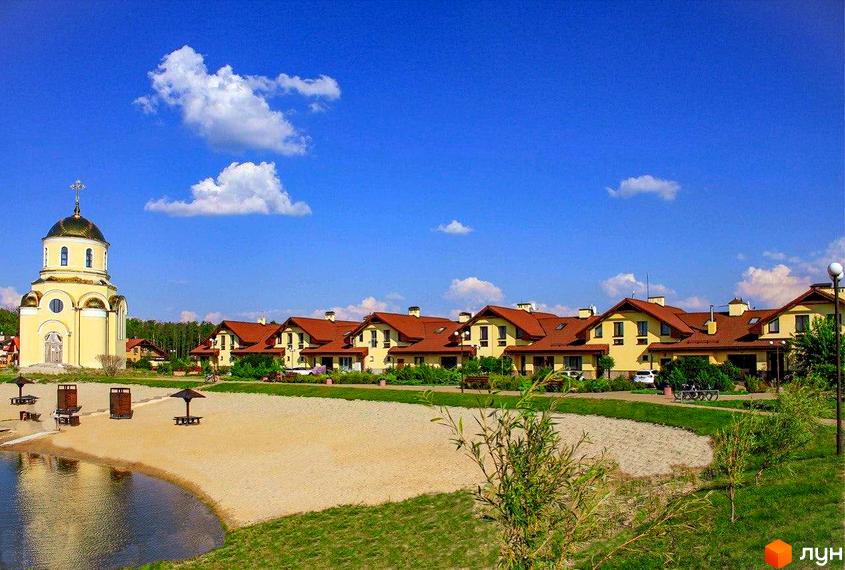 Житловий комплекс Северинівка з жовтими будинками з теракотовими дахами. Поруч піщаний пляж, озеро та православна церква.