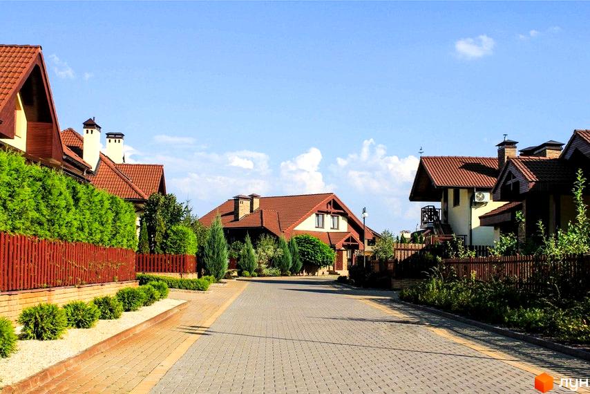 Котеджне містечко Северинівка: будинки з черепичними дахами та доглянутою прибудинковою територією. Вулиця з бруківкою та зелені насадження створюють атмосферу затишку.