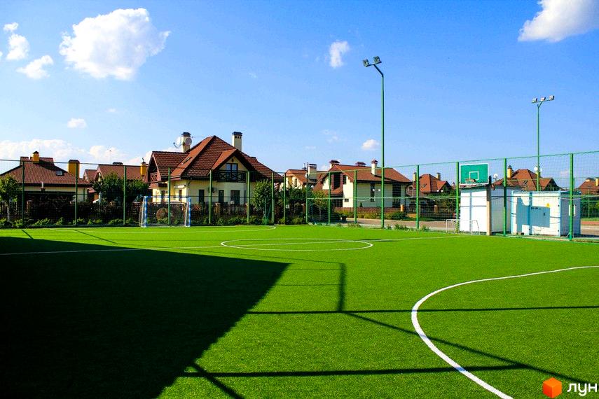 Котеджне містечко Северинівка. На фото зображено будинок з коричневою черепицею та зеленою прибудинковою територією з футбольним полем.