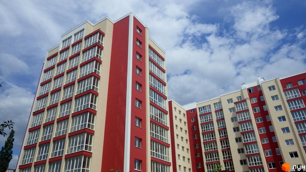 Зображення фасаду Житлового комплексу Мрія. Багатоповерховий будинок з великими вікнами на фоні хмарного неба.