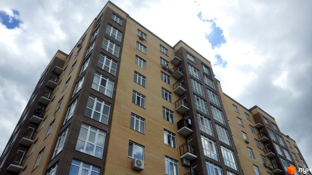 Житловий комплекс Зелений – це сучасна багатоповерхова новобудова з цегляним фасадом жовтого та коричневого кольорів. Будинок має багато вікон та балконів, що створює привабливий зовнішній вигляд.