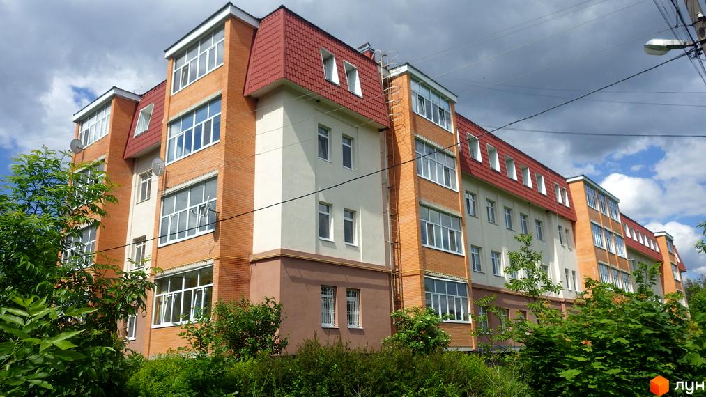 Новобудова на вул. Гайок, 224б: багатоповерховий будинок з червоним дахом, цегляним фасадом та зеленими насадженнями навколо.