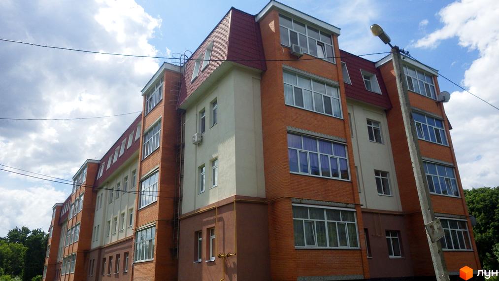 Фасад житлового комплексу на вул. Гайок, 224б, з цегляним оздобленням та великими вікнами. Будинок має кілька поверхів та червоний дах.