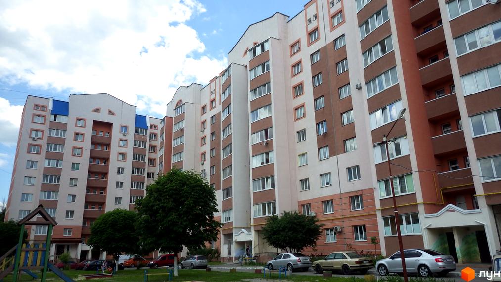 Зовнішній вигляд житлового комплексу на вул. Леваневського, 70, з багатоповерховими будинками та прибудинковою територією з дитячим майданчиком та автомобілями.