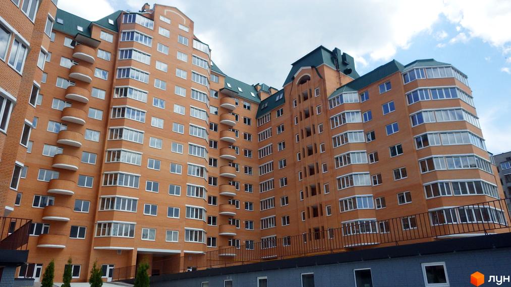 Висотна новобудова з цегляним фасадом та балконами. На території ЖК Набережний є зелені насадження.