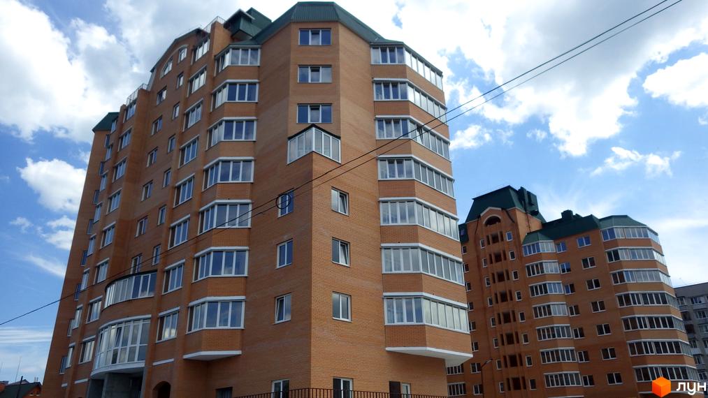 Високі будинки з цегли з великою кількістю вікон. Житловий комплекс Набережний з гарним виглядом на небо.