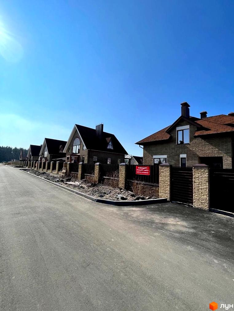 Котеджне містечко КМ Барвіта: фасади будинків з цегли та коричневої черепиці, огороджена територія з кованими воротами та парканом.