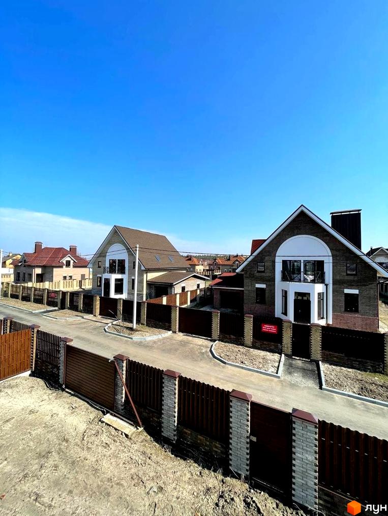 Котеджне містечко КМ Barvita. Сучасні двоповерхові будинки з цегляним фасадом та коричневими дахами, огороджені парканом, розташовані на вулиці.