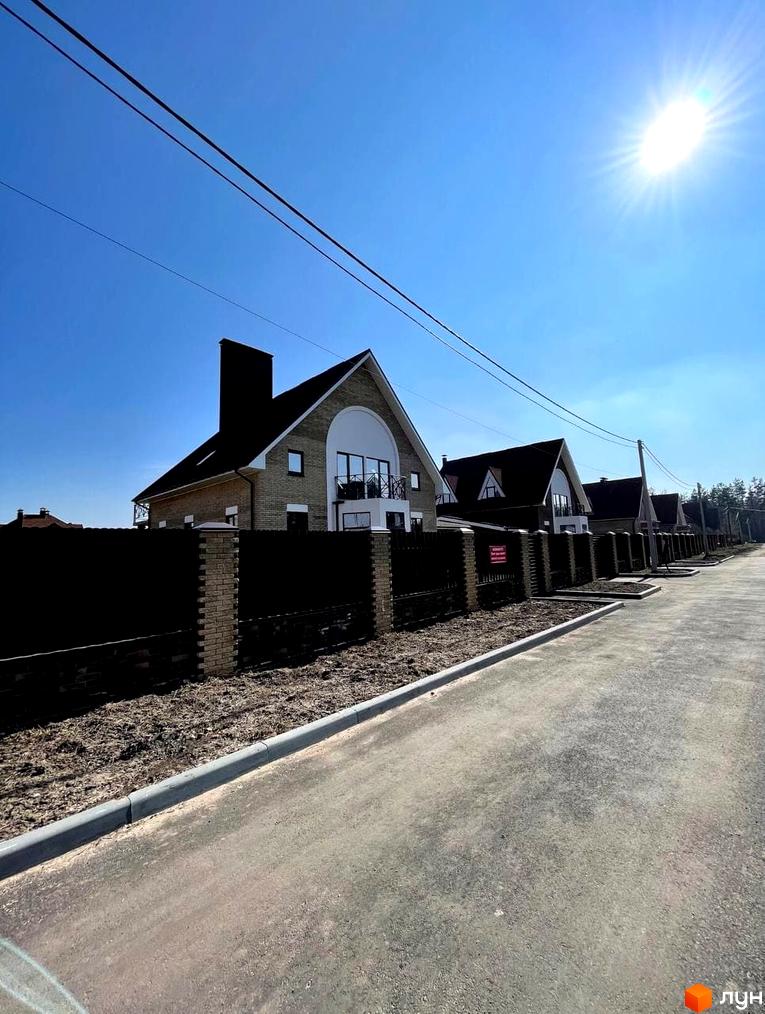 Котеджне містечко КМ Барвіта: фасади будинків з цегли та темними дахами, огороджена територія з парканом та бруківкою.