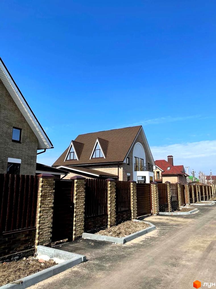 Котеджне містечко КМ Барвіта: цегляні будинки з коричневими дахами та парканами вздовж вулиці.