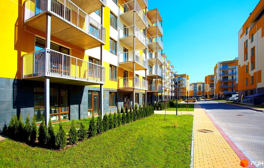 Житловий комплекс Ліпінка з жовтою фасадною обробкою та балконами. Прибудинкова територія з зеленими насадженнями та тротуарами.